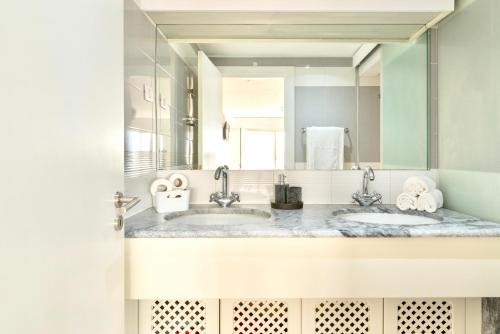 a bathroom with two sinks and a large mirror at Swimming pool apartment with private parking in Lisbon