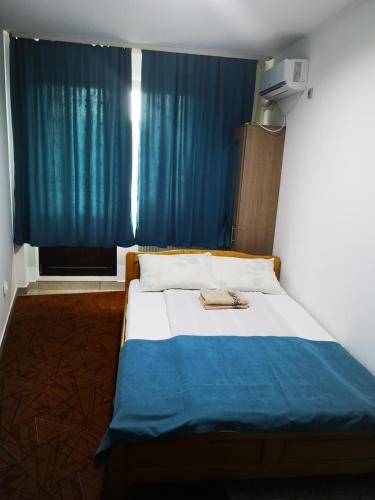 a bed in a room with a blue curtain at Pensiunea Mikelis International in Curtea de Argeş
