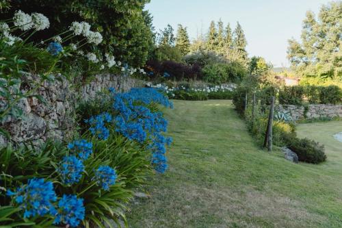 a garden with blue flowers and a stone wall at Casa Agricola da Levada Eco Village in Vila Real