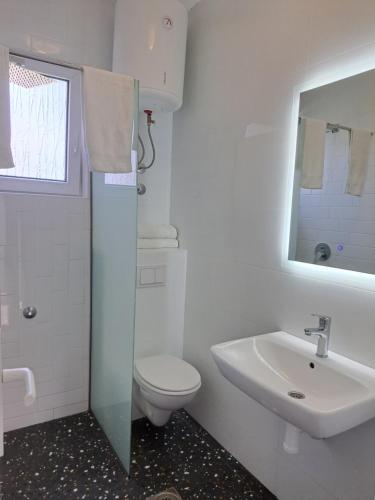 a white bathroom with a toilet and a sink at Black & White in Sutomore
