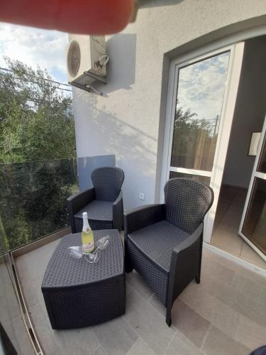 a balcony with two chairs and a table with a bottle on it at Black & White in Sutomore