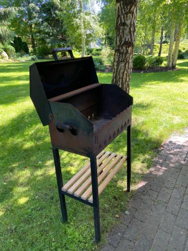 a grill sitting on a park bench next to a tree at Romantic cozy house Kirzacinas pirts with sauna close to seaside in Skulte