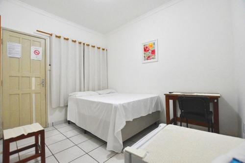 a room with a bed and a table and a chair at Hotel Tapajós in Cuiabá