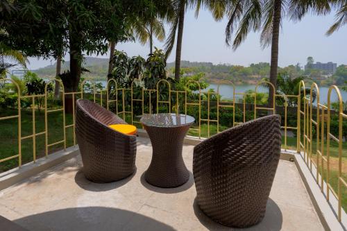 three wicker chairs and a table in front of a fence at Ras Resort By Treat Silvassa in Silvassa