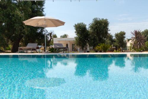 a large blue swimming pool with an umbrella at Le Dimore Di Speziale in Fasano