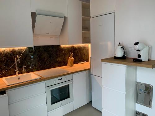 une cuisine avec des armoires blanches et un comptoir dans l'établissement Baltica Heaven - Apartament dwupoziomowy przy plaży, à Rogowo