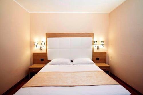 a bedroom with a large white bed with two pillows at Momi's Hotel in Cavarzere