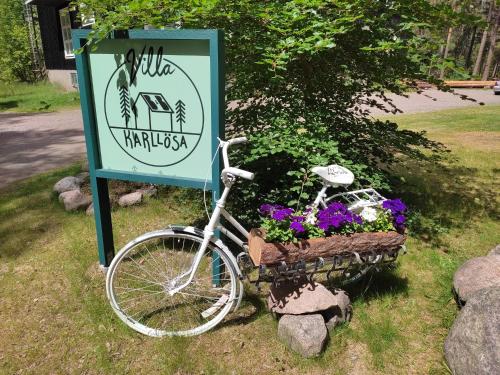 a bike parked next to a sign with flowers at Villa Karllösa Bed and Breakfast in Målilla
