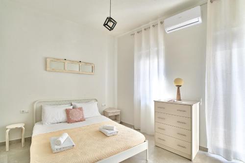 a white bedroom with a bed and a dresser and a window at Villa Vagelia in  Episkopi (Chania)