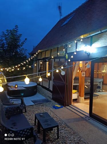 d'une terrasse avec une table et des lumières sur une maison. dans l'établissement Sauna & Double Jacuzzi intérieur et sous les étoiles 1h30 Paris, à Ladon