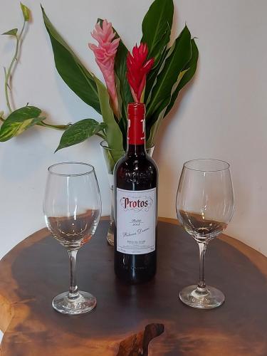 a bottle of wine and two glasses on a table at Ibiza Tropical Beach Villas in Uvita