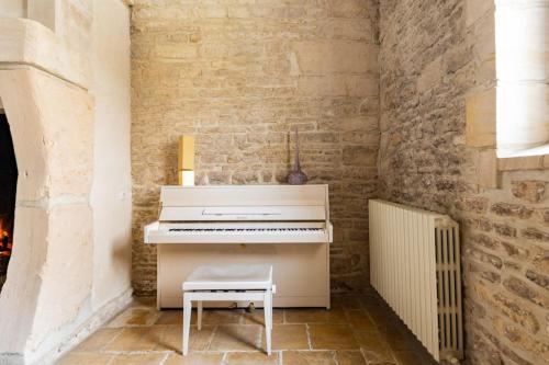 a white piano in a room with a brick wall at L'Ecurie Gourmande in Thaon
