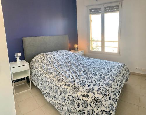 um quarto com uma cama com um edredão azul e branco em Joli 2p climatise dans résidence calme et securisée avec piscine em Antibes