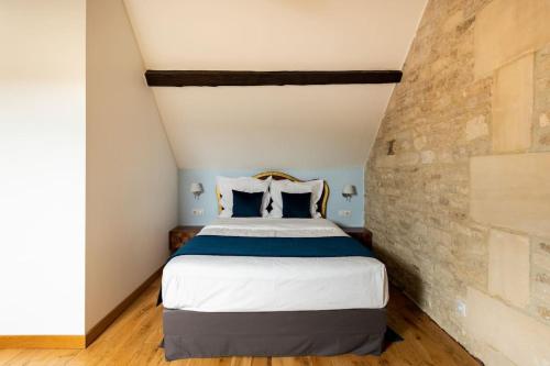 a bedroom with a bed with a stone wall at L'Ecurie Gourmande in Thaon