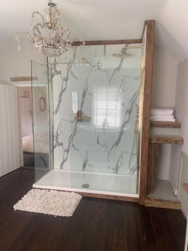 a shower with a glass door in a room at Blythe Cottage in Long Melford