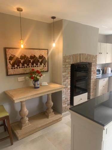 a kitchen with a counter with a fireplace in it at Blythe Cottage in Long Melford