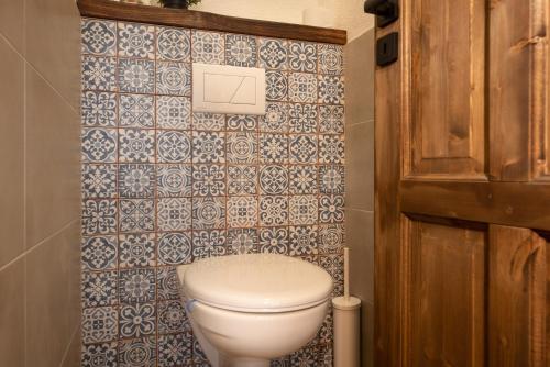 a bathroom with a toilet and a tiled wall at Wellness Chata Chmaroška - Telgárt Resort in Telgárt