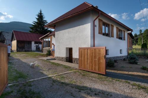 a woman standing next to a house with a wooden door at Wellness Chata Chmaroška - Telgárt Resort in Telgárt