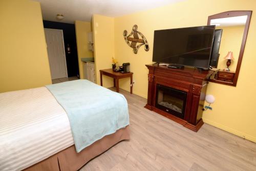 a bedroom with a bed and a flat screen tv at Casa Grande Inn in Qualicum Beach