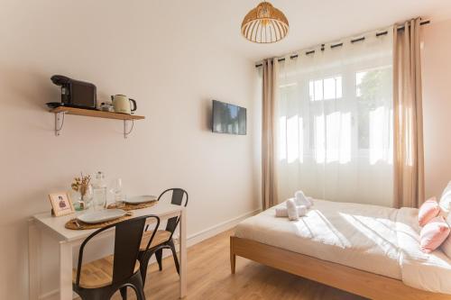 een slaapkamer met een tafel, een bed en een bureau bij Les Studios du Parc Bordelais - Le Canelé in Le Bouscat