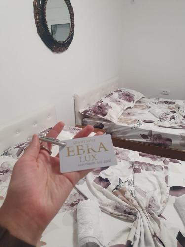 a person holding a pair of scissors over a bed at Ebra Lux Apartmani in Dobra Voda