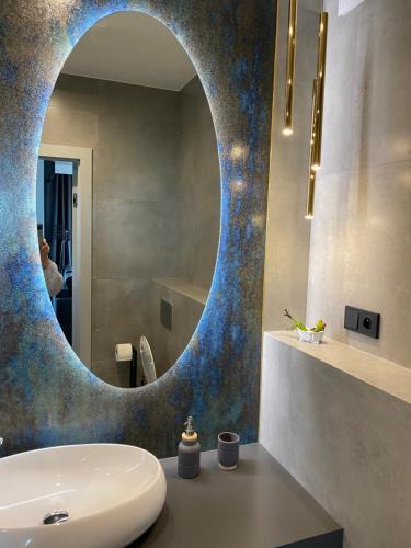 La salle de bains est pourvue d'un miroir rond au-dessus d'un lavabo. dans l'établissement Apartament Rzekotka Zielona Dereniowa 60, à Varsovie