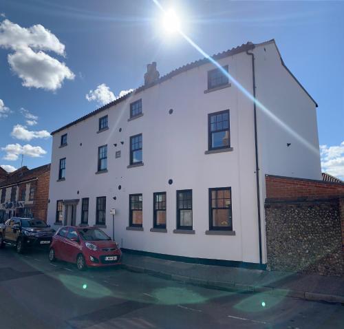 a white building with cars parked in a parking lot at 'The View' Penthouse Apartment Number Four Lees Terrace in Holt