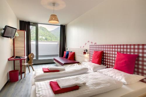 Habitación de hotel con 2 camas y almohadas rojas y blancas en MEININGER Hotel Salzburg City Center, en Salzburgo
