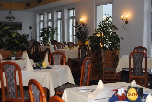Hotel Stadt Spremberg في شبرمبرغ: مطعم بطاولات بيضاء وكراسي ونباتات