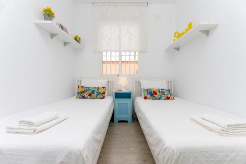 two beds in a room with white walls at Livemálaga Gordon Home in Málaga