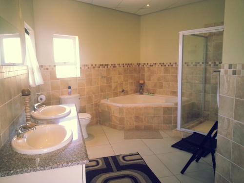 a bathroom with two sinks and a tub and a shower at The Homestead Margate - South Africa in Margate