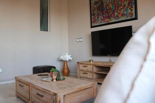 a living room with a wooden coffee table and a flat screen tv at 1007-Stunning Studio apt with incredible Joburg views in Johannesburg