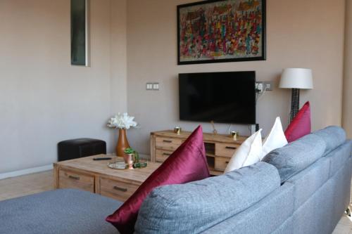 a living room with a blue couch with colorful pillows at 1007-Stunning Studio apt with incredible Joburg views in Johannesburg