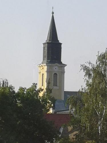 a tall church steeple with a clock on it at Levendula Apartman in Makó