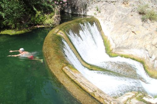 a man in a pool of water next to a waterfall at B&B Finca la Yuca "Un paraíso en Ontinyent" in Ontinyent