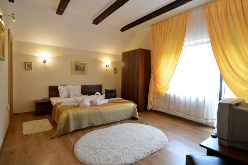 a bedroom with a bed with white pillows and a television at Bucuria Muntelui in Bran