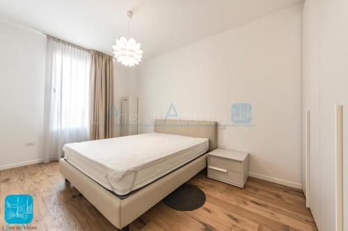Habitación blanca con cama y lámpara de araña. en Residence Wave Plus, en Lido di Jesolo