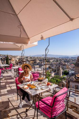 a woman sitting at a table with food on a balcony at Charming Cave Hotel in Goreme