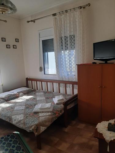 a bedroom with a bed and a tv and a window at ANNAS COTTAGE in Skala Sotiros