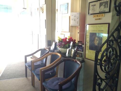 a room with two chairs and a table with flowers at Hôtel Stanislas sans ascenseur in Paris