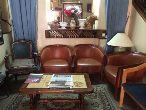 a waiting room with leather chairs and a table at Hôtel Stanislas sans ascenseur in Paris
