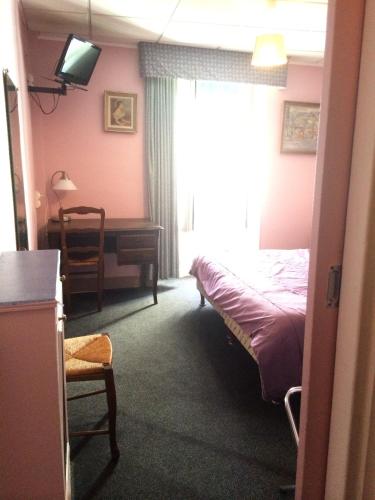 a bedroom with a bed and a desk and a television at Hôtel Stanislas sans ascenseur in Paris