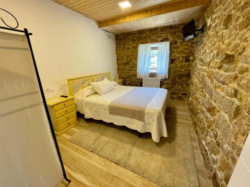 a bedroom with a bed and a stone wall at LAR DE SUSA in Pontevedra