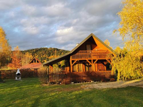 a large wooden house with a deck on a field at Pokoje Gościnne Agnes in Sanok