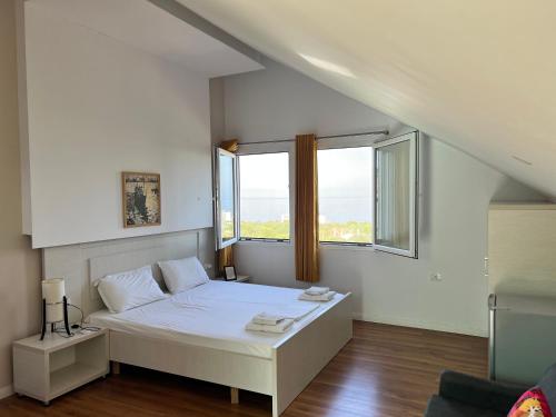 1 dormitorio blanco con 1 cama y 2 ventanas en Aria Guest house, en Himare