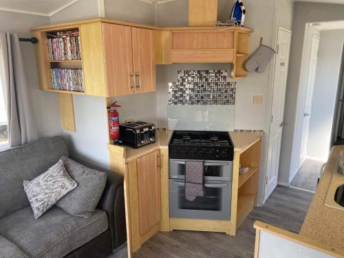 a small kitchen with a stove and a couch at Legacy on Highfields in Skegness