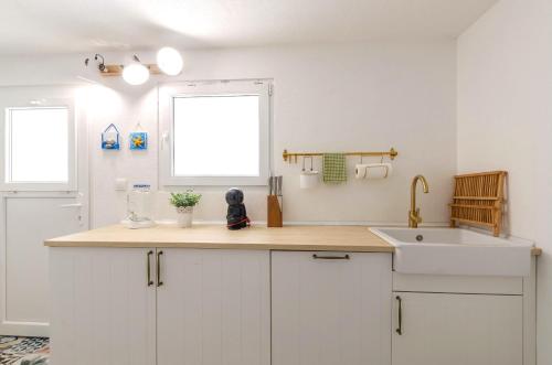 a kitchen with white cabinets and a sink and a window at Summer House Bougainvillea by Dubrovnik Colors in Blato