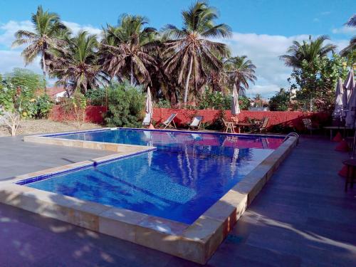 uma piscina com água azul e palmeiras em Pousada Escape em Barra Nova