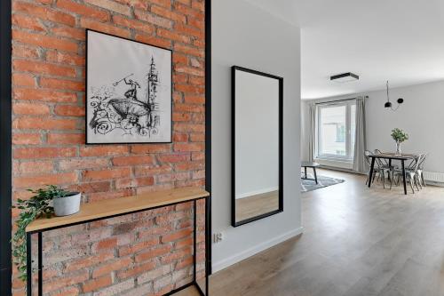 an empty living room with a brick wall and a mirror at Przystań Letnica Seaside by Downtown Apartments in Gdańsk