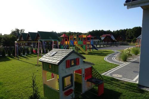 un parque infantil con una pequeña casa en el césped en Ośrodek Wypoczynkowy Domki Nadika en Bobolin